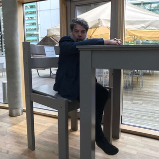 foto von mir wie ich an einem überdimensionierten tisch sitze