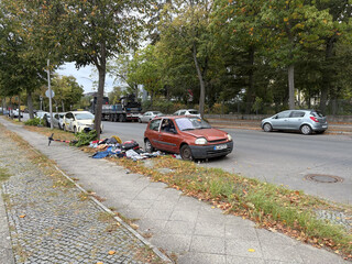 ein verlassenes, aufgebrochenes auto und ein haufen m&uuml;ll drumrum am strassenrand