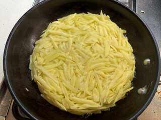 geriebene, getrocknete kartoffeln mit etwas butter bei sehr niedriger hitze in einer pfanne.