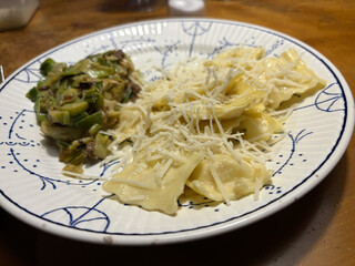 ravioli mit angebratenem sahne-poree auf einem weissen teller mit klassischem blauem muster auf einem holztisch