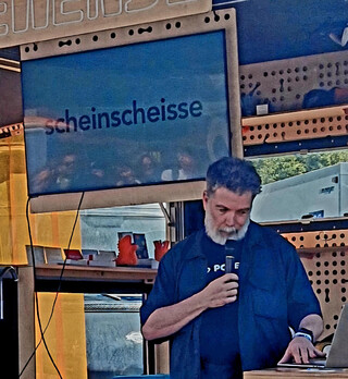 auf dem monitor steht: „scheinscheisse“, ich spreche in ein mikorofon