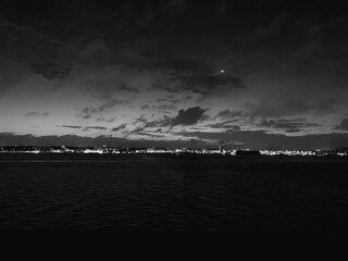 blick auf die nächtliche ostsee von einem schiff aus, am horizont sieht man lichter, der himmel ist leicht erleuchtet