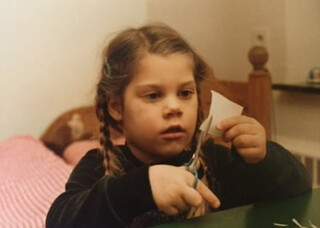 elena schneidet ein blatt papier und ist dabei hochkonzentriert. foto ungef&auml;hr aus dem jahr 1980, aufgenommen in zuhause in kornelim&uuml;ster.