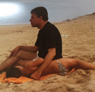 elena und unser vater im frankreichurlaub in lacanau ocean am strand. foto ungef&auml;hr um das  jahr 1980. mein vater blickt auf das meer, elena schl&auml;ft an seiner seite.