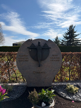 ein l&auml;chelnder jesus h&auml;ngt an einem grabstein und tr&auml;gt am rechten arm ein herz