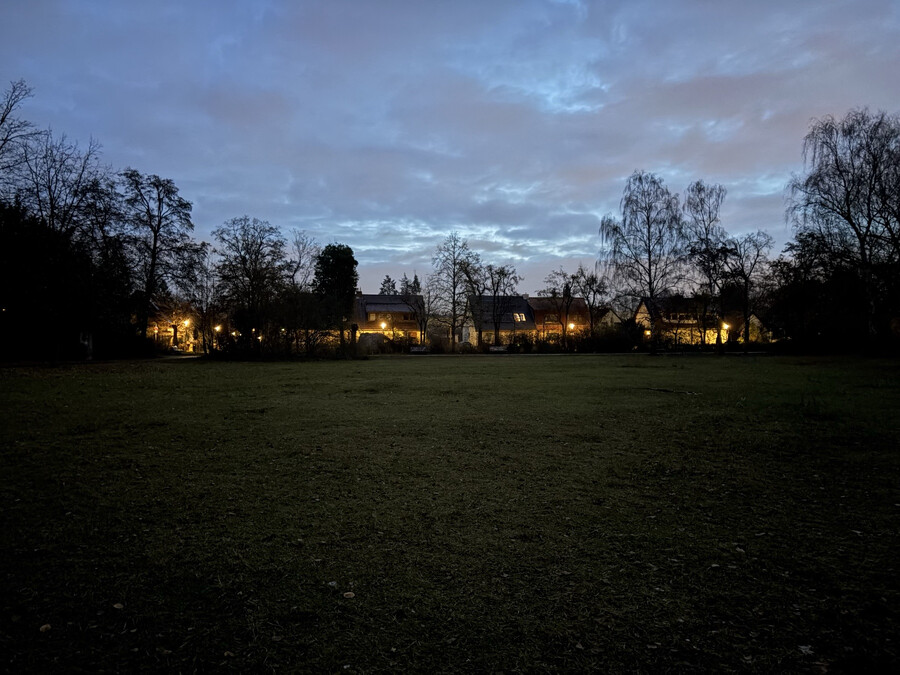 foto von vom morgengrauen im goethepark. man sieht die hell erleuchteten einfamiloienhäuser in der dämmerung glühen.
