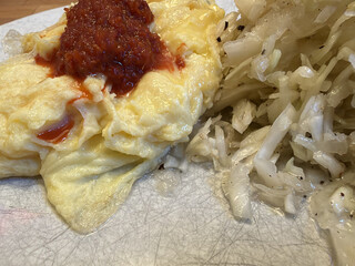 r&uuml;hrei mit einem klecks sambal olek und griechischer krautsalat auf einem weissen teller