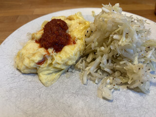 r&uuml;hrei mit einem klecks sambal olek und griechischer krautsalat auf einem weissen teller
