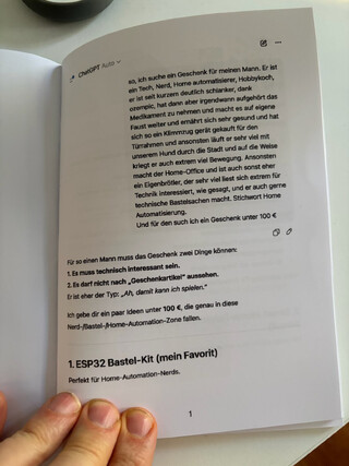 foto des buchs, das die beifahrerin mir geschenkt hat. man sieht dialoge die sie mit chatGPT geführt hat um (vergeblich) ein geschenk gü mich zu finden.