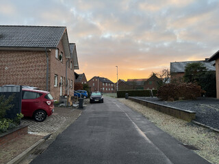ortskern von karken, der himmel ist orange-blau, man sieht leichten rauch aus schornsteinen aufsteigen