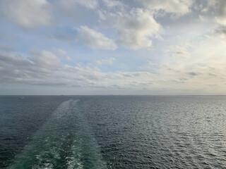 foto vom heck eines schiff auf das kielwasser, das sich als helle spur durch die graublaue ostsee zieht