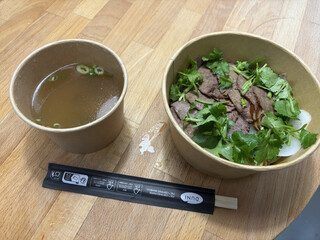 einwegverpackungen der noodle bowl von chen&rsquo;s beef nood house. links in alufolie eingeschlagen die br&uuml;he, rechts die nudeln mit der einlage. die einwegverpackungen sind ge&ouml;ffnet.