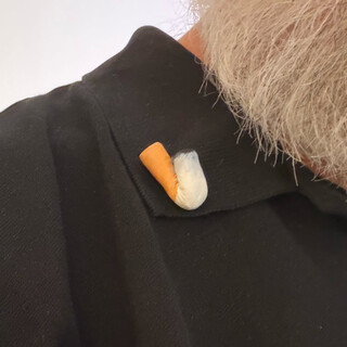 ein polohemd mit einer brosche am kragen. die brosche sieht aus wie eine ausgedrückte zigarettenkippe