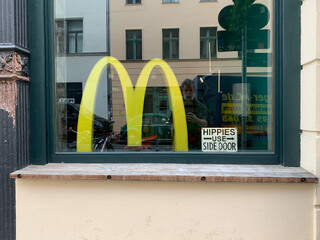bild eines galerie schaufensters mit einem „vintage“ mcdonalds M und einem fake „HIPPIES USE SIDE DOOR“ schild