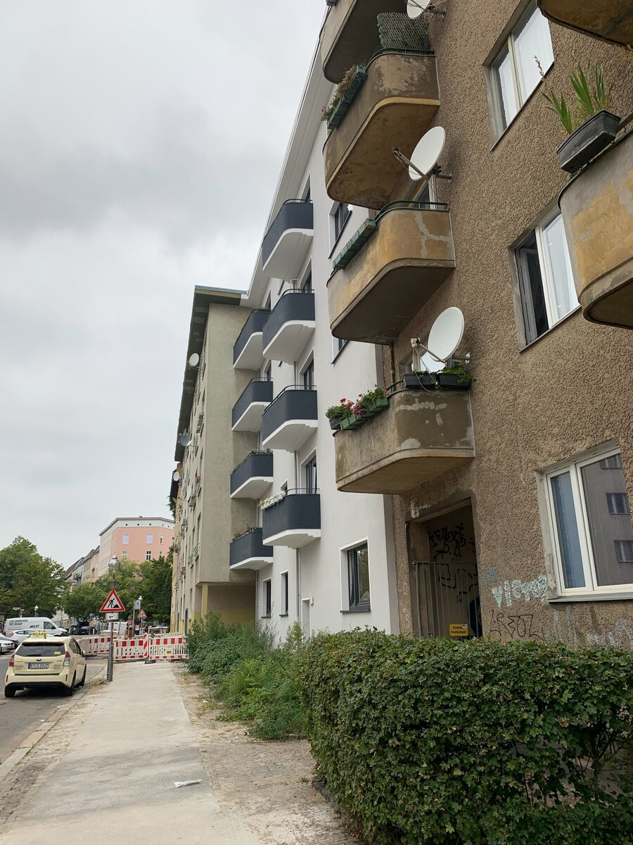 foto einer von zwei baugleichen häusern, eine fassade ist saniert, die andere nicht