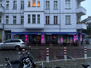 caf&eacute; an der br&uuml;sseler strasse im wedding. das caf&eacute; ist geschlossen, aber die pinke aussenbeluchtung leuchtet gegen das tr&uuml;be morgenlicht an.