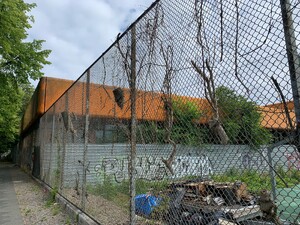 bild der verlassenen schule an der putbusser strasse. man sieht im zaun recht dicke baumstücke hängen.