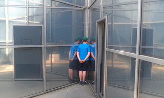 das kind steht in der spitzen ecke einer glaswand und reflektiert sich dreifach