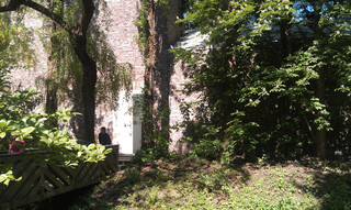 eins der backsteingeb&auml;ude der museumsinsel hombroich im sonnenschein. davor stehen m&auml;chtig grosse b&auml;ume.