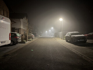 nachtbild des johann frenken wegs in karken, es ist neblig und es liegt raureif, die strassenlaternen beleuchten den nebel.