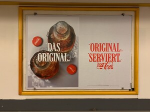 foto eines coca cola werbeplakats mit der aufschrift „das original“ und „original serviert“