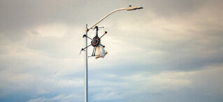 screenshot aus pluribus’ fünfter folge, der eine drohne zeigt, die sich um eine strassenlaterne gewickelt hat