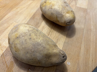 zwei ungeschälte pommes auf einem holztisch.