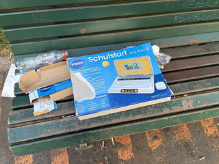 verpackungskarton auf einer parkbank mit der aufschrift „schulstart“ und dem bild eines kinderlaptops mit LCD display