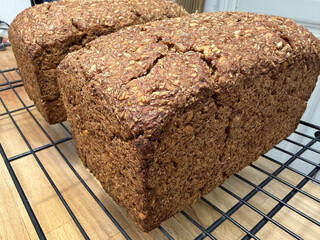 nahaufnahme des fertig gebackenen schwarzbrot. man sieht das es viele körner enthält, die kruste ist oben leicht aufgebrochen