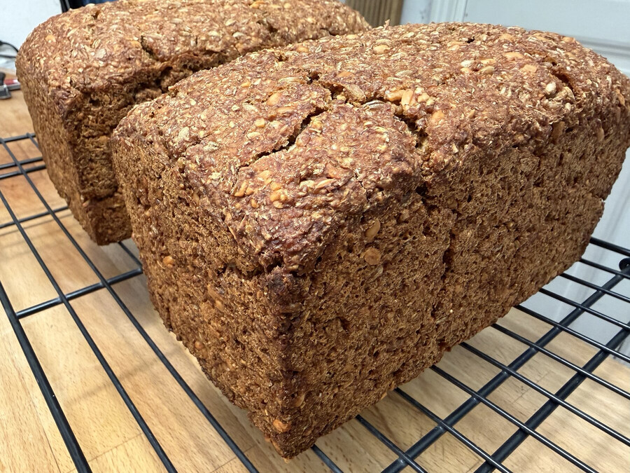 nahaufnahme des fertig gebackenen schwarzbrot. man sieht das es viele körner enthält, die kruste ist oben leicht aufgebrochen