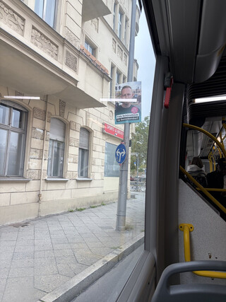 ein wahlplakat aus dem bus durchsfenstre fotografiert. auf dem plakat erkennt man, dass der kandidat seine parteizugehörigkeit (CDU) lieber nicht nennt. auf dem plakat steht nur sein name und ein slogan.