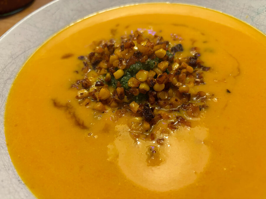 foto von einem teller kürbissuppe mit kokosmilch, spinat-knoblauch-pesto und geröstetem mais