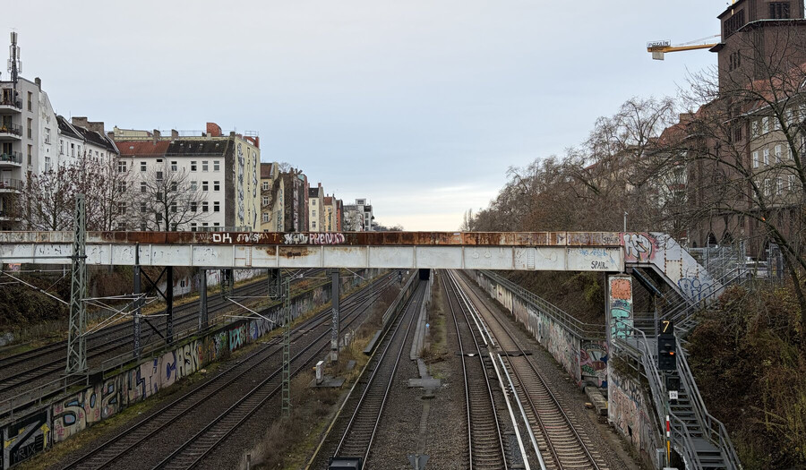 foto von von einer fussgöngerbrücke über die bahngleise zwischen gesundbrunnen und schönahuser allee. alles sieht grau-braun aus, ausser ein paar weiss-verwaschender mehrfamilienhöuser links.